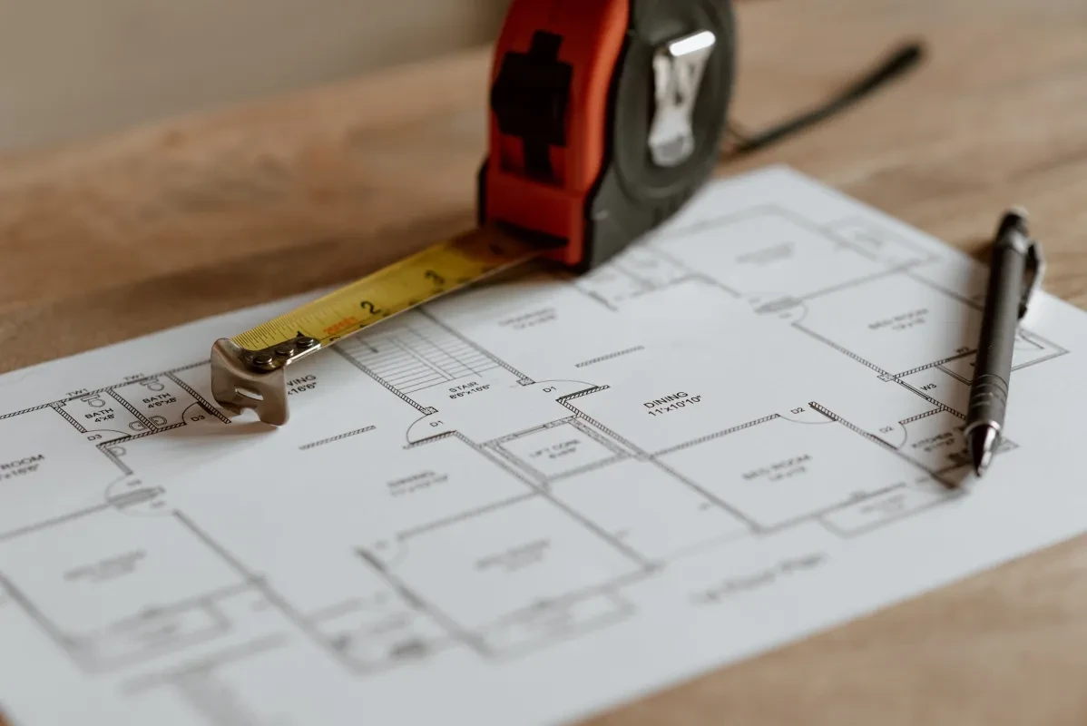 A tape measure and pen sitting on top of construction floor plans
